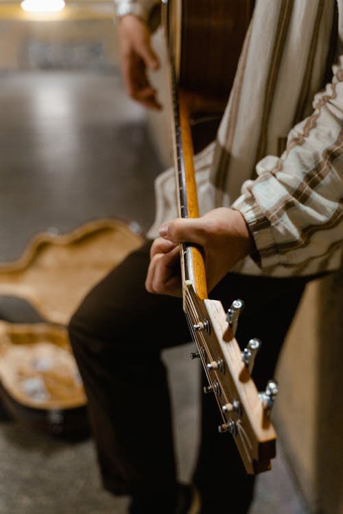 Man in Brown and White Stripe Dress Shirt Playing Guitar