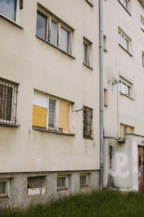 Free A vertical shot of an urban apartment building facade with graffiti and boarded windows. Stock Photo