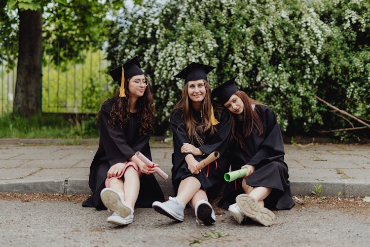 Young Graduates Sitting On The Curb