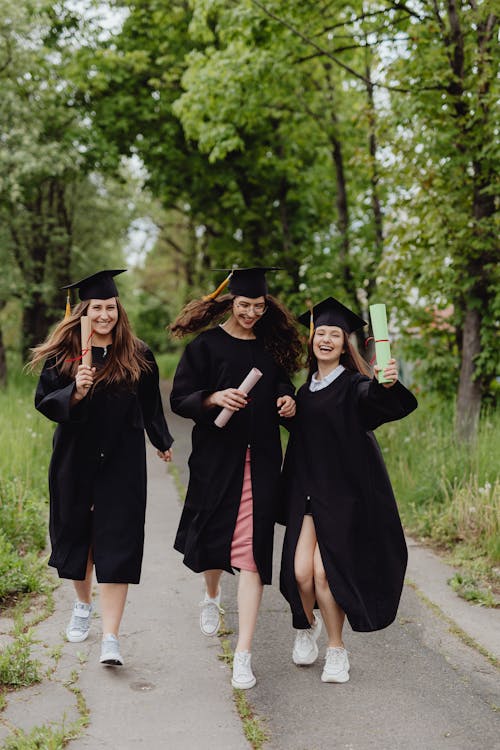 Free Women Wearing Graduation Caps Walking Stock Photo