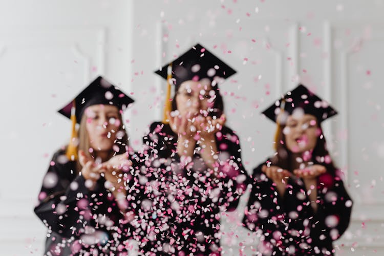 Group Of Graduating Women Blowing Confetti