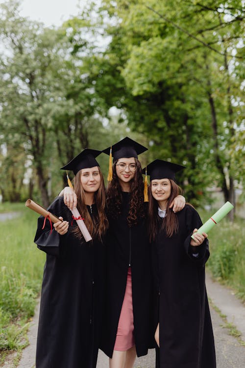 Women Wearing Academic Dress Holding Diplomas