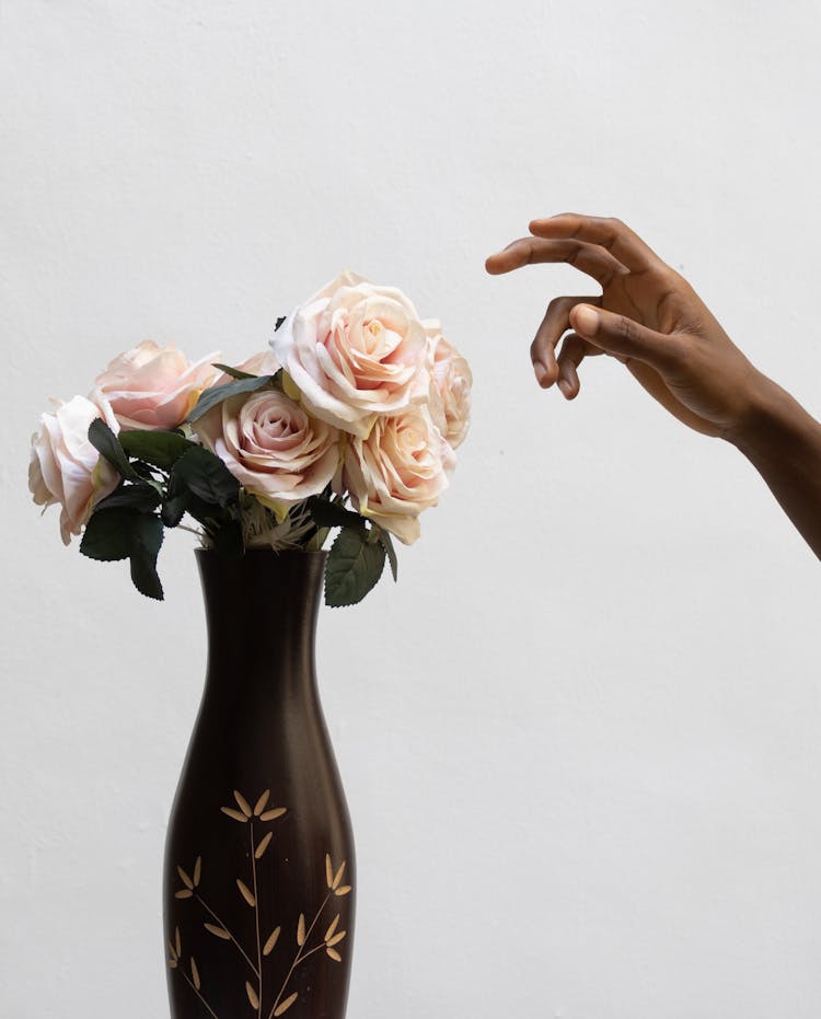 Crop Ethnic Person With Blossoming Roses In Vase