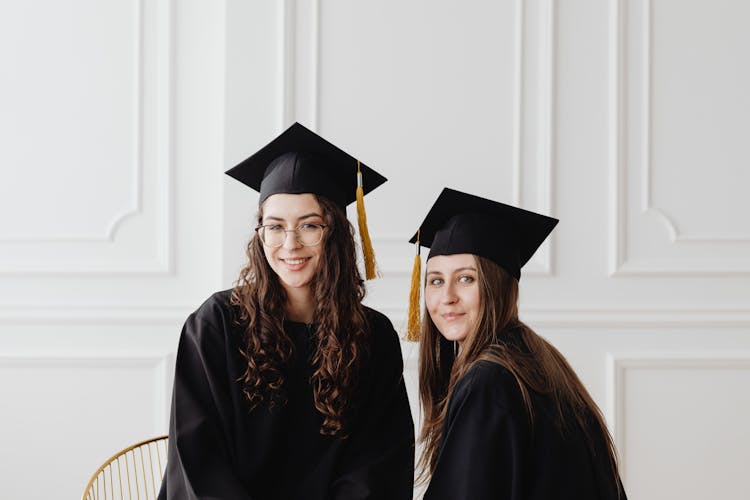 Young Graduates In Their Academic Dress And Graduate Caps