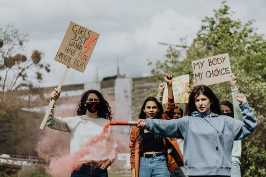 A diverse group of women protesting outdoors holding signs advocating for women's rights and freedom.