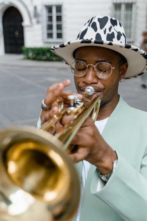 Free A stylish street musician performing with a trumpet outdoors in daylight. Stock Photo