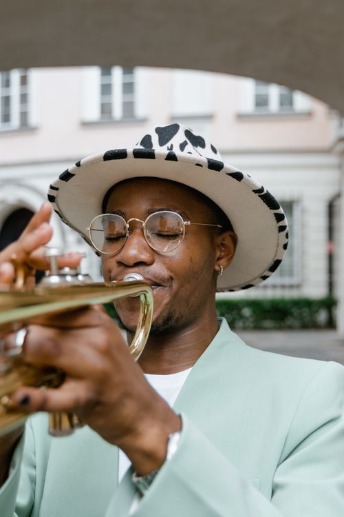 Free Expressive musician performing on trumpet with unique style in a city setting. Stock Photo