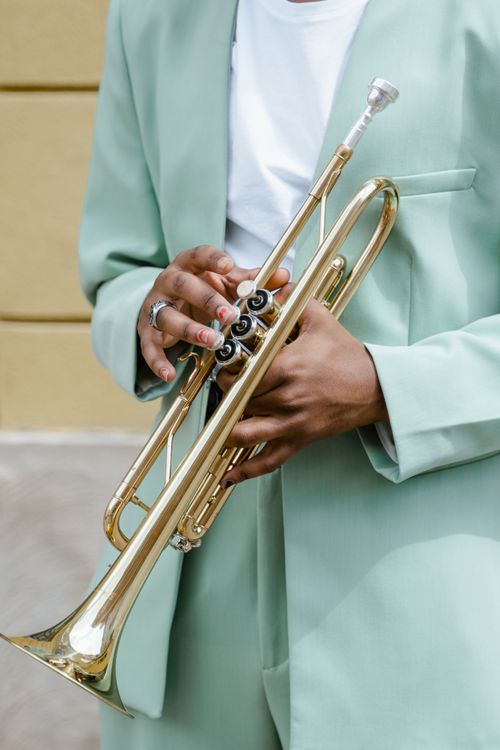 Free Close-up of a musician in a mint green suit playing a brass trumpet outdoors. Stock Photo