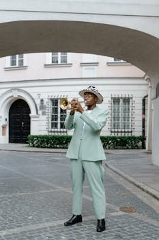 Man in stylish suit playing trumpet on a city street, showcasing urban art.