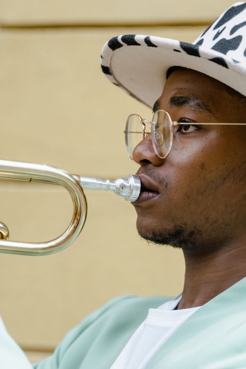 Free Close-up of an African American musician in a fedora playing trumpet outdoors. Stock Photo