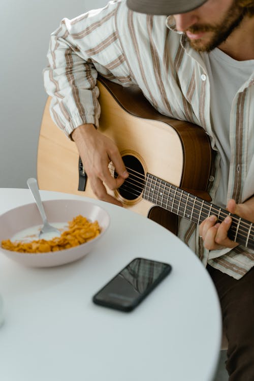 Man in White and Brown Stripes Button Up Shirt Playing Guitar