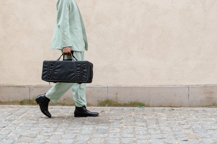 Person Walking In The Street Carrying A Black Bag