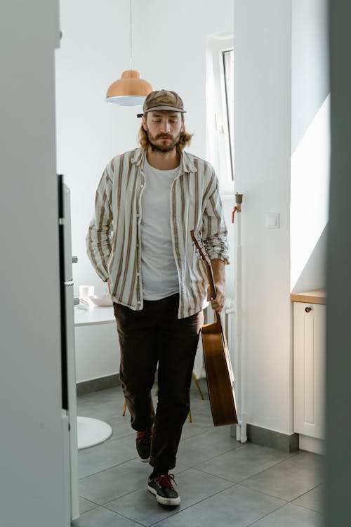 Man in White and Gray Striped Dress Shirt and Black Pants Bringing His Guitar