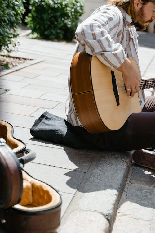 Person Playing Brown Acoustic Guitar