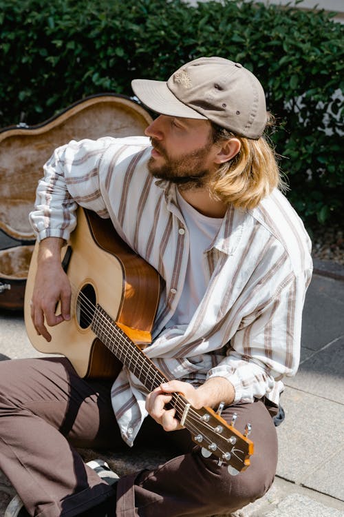 Man in White and Brown Stripes Dress Shirt Playing Acoustic Guitar