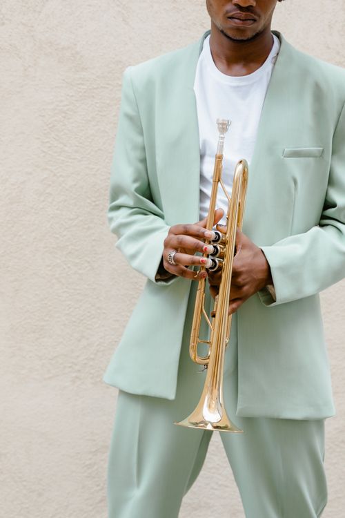 Free Stylish musician in mint suit holding a trumpet, showcasing modern elegance and music passion. Stock Photo
