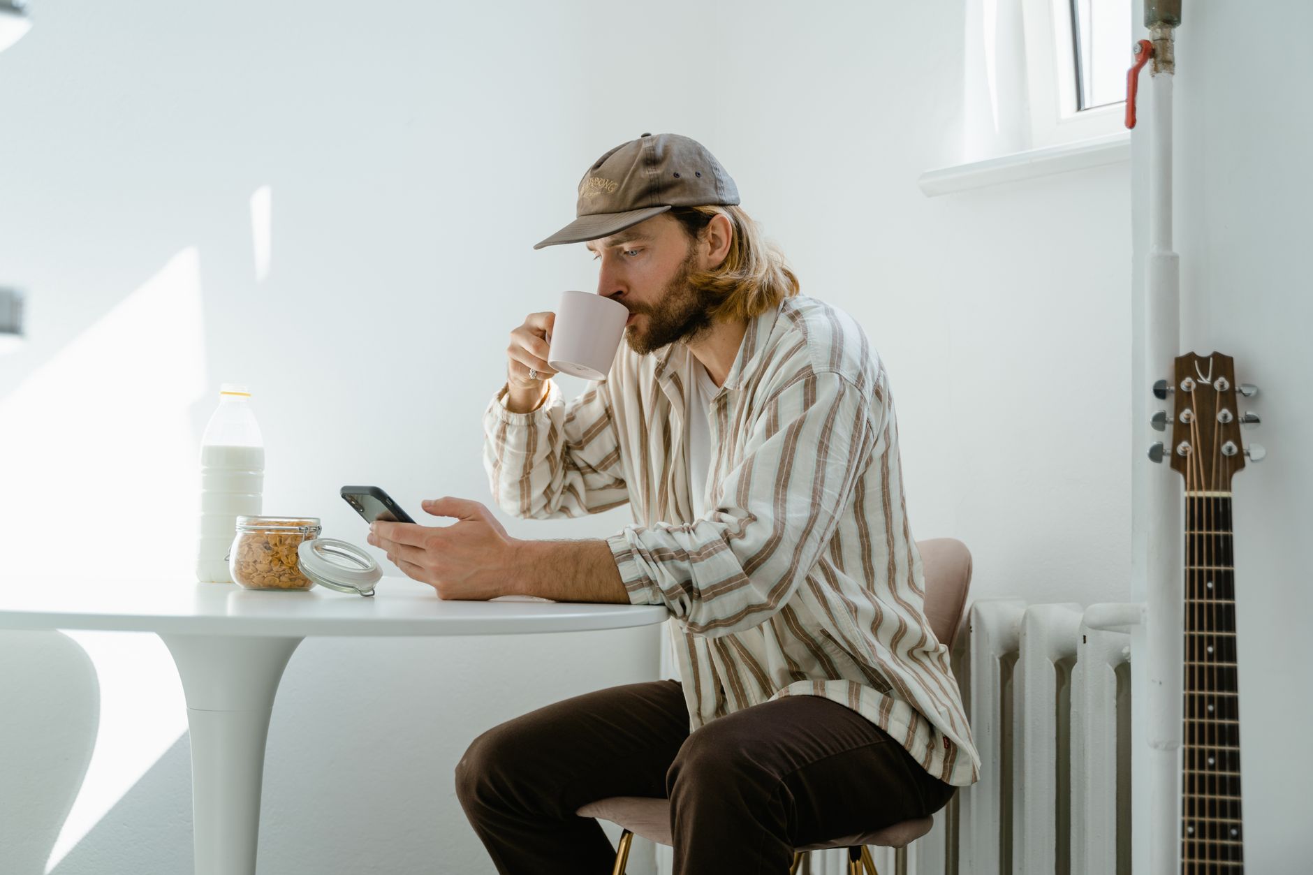 A client checking their phone at the kitchen table with a coffee in the morning