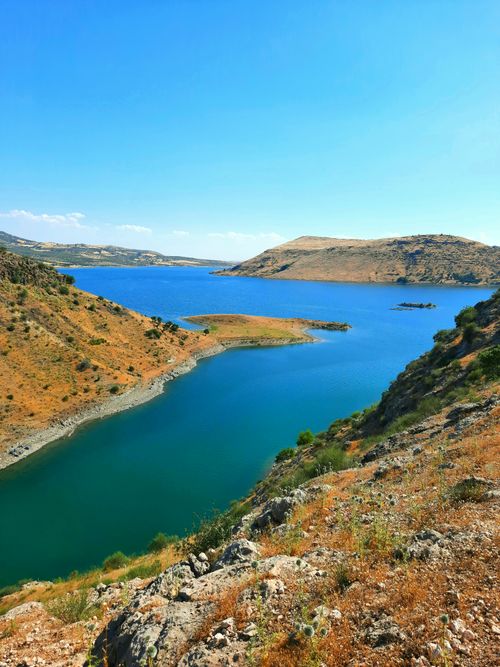 Free A breathtaking view of a vibrant blue lake surrounded by arid hills under a clear sky. Stock Photo