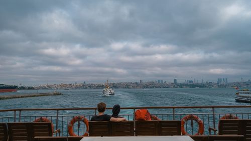 Free Couple sits on a ferry with stunning Istanbul skyline view over the sea, under a cloudy sky. Stock Photo