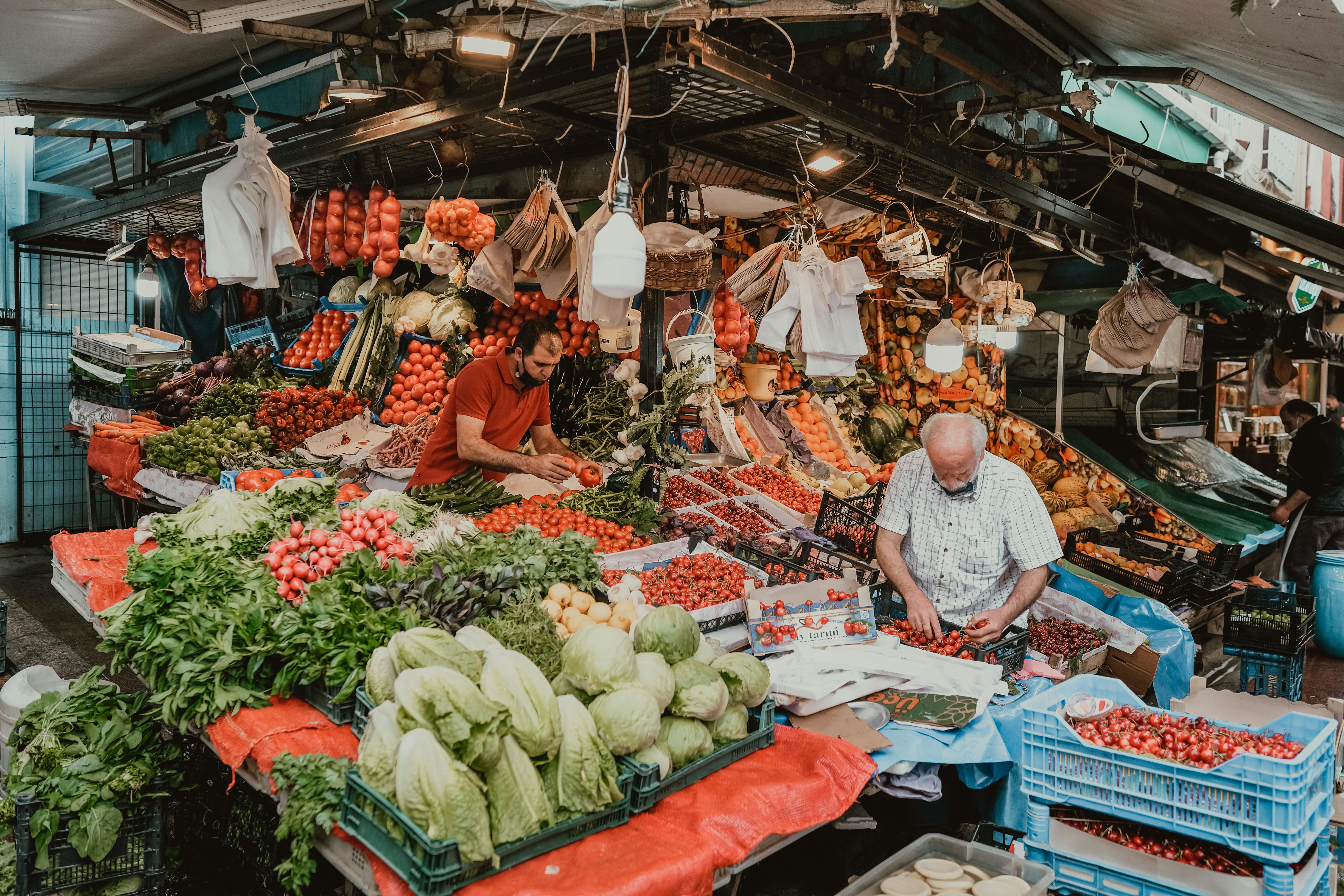 Outdoor market scene showcasing men selling a variety of fresh fruits and vegetables.