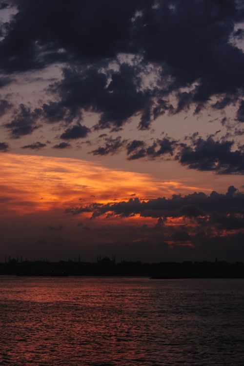 Free Beautiful sunset with vivid clouds reflecting over the ocean's surface. Stock Photo