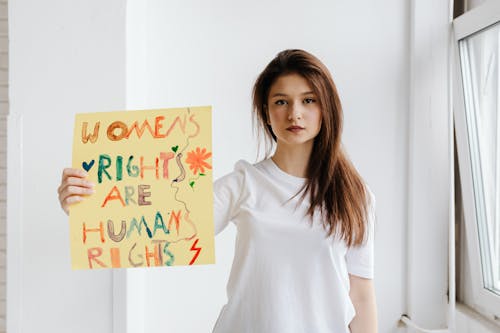 Free Woman in White Crew Neck T-shirt Holding a Poster Stock Photo
