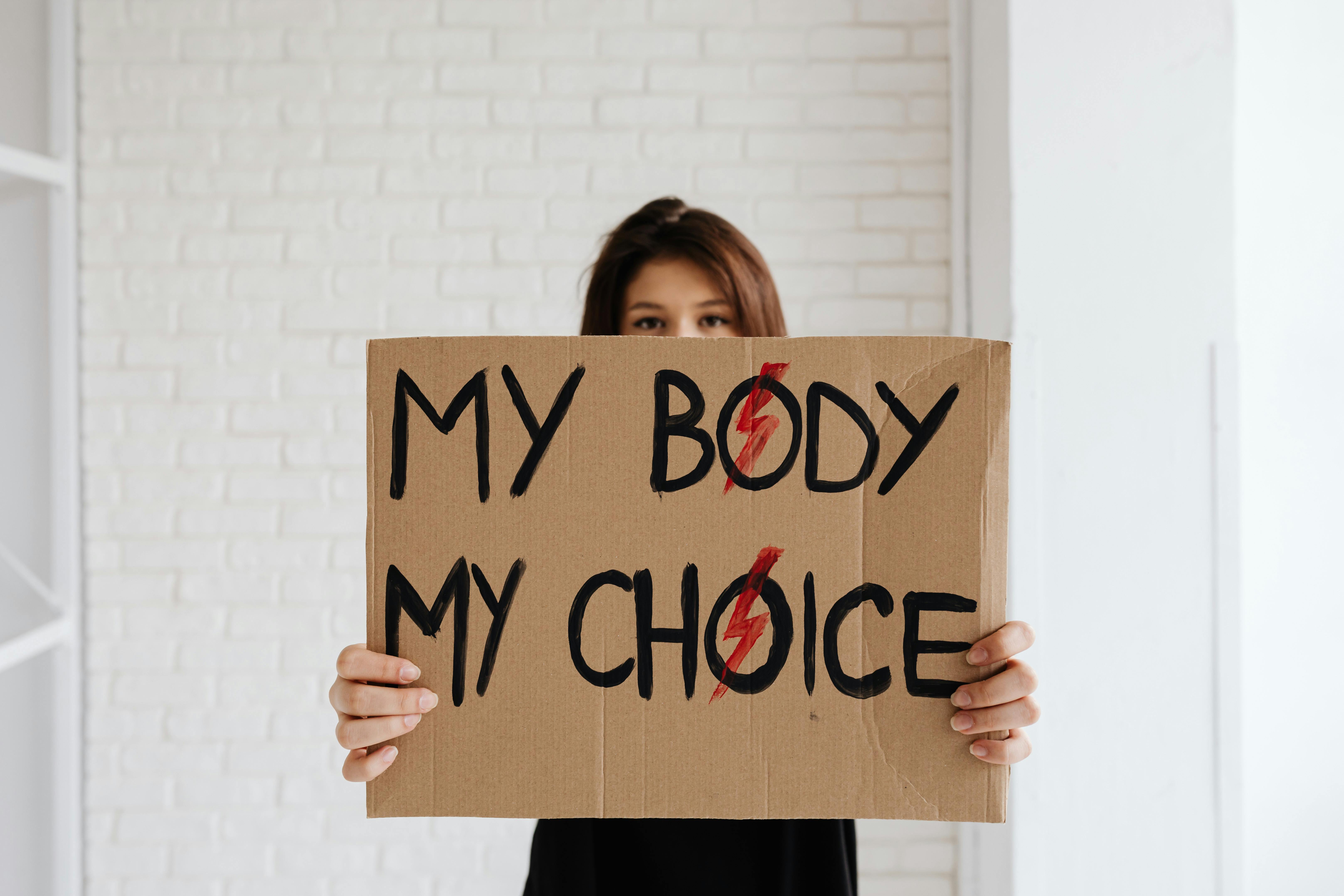 A young woman holding a sign that reads "My Body My Choice," advocating for women's rights and freedom of choice.