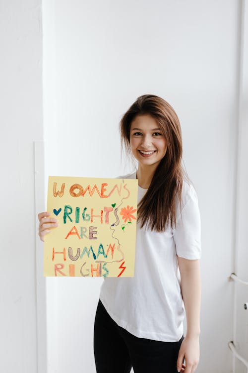 Woman in White Crew Neck T-shirt Holding a Poster