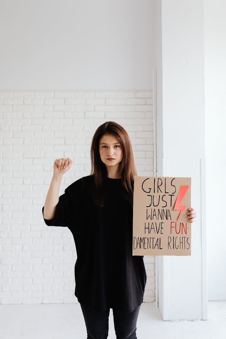 Woman In Black Shirt Holding A Cardboard Poster