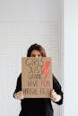 Woman in Black Shirt Holding a Brown Cardboard Poster