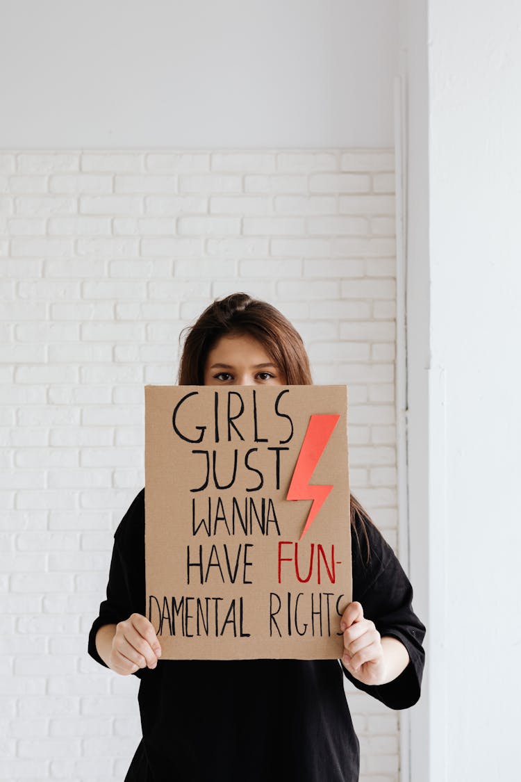 Woman In Black Shirt Holding A Brown Cardboard Poster