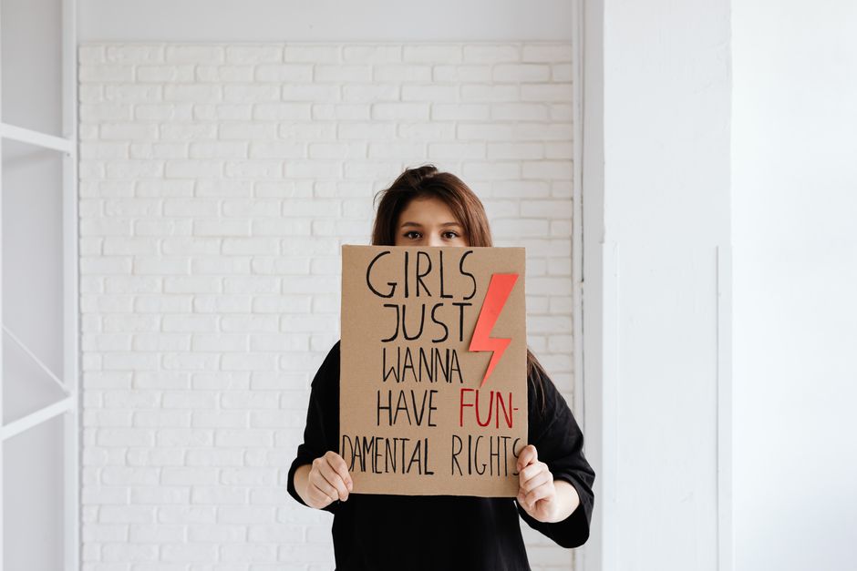 Mujer sosteniendo un cartel que aboga por los derechos fundamentales de las mujeres en interiores.