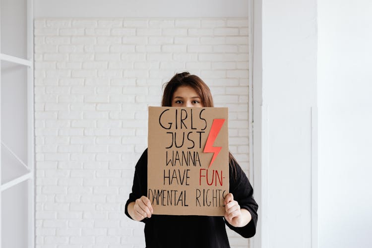 Woman In Black Shirt Holding A Brown Cardboard Poster