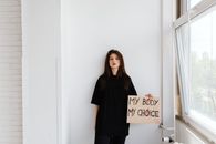 Woman in Black Shirt Leaning White Concrete Wall