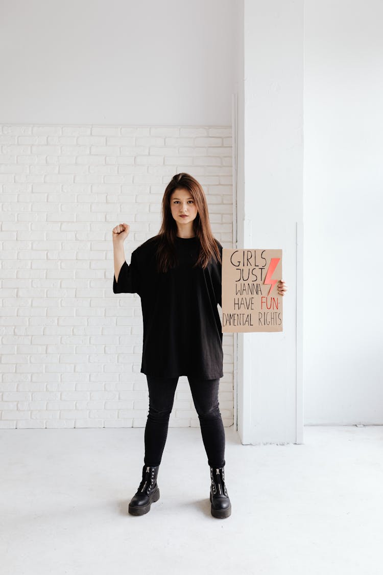 Woman In Black Shirt And Black Pants Holding A Poster