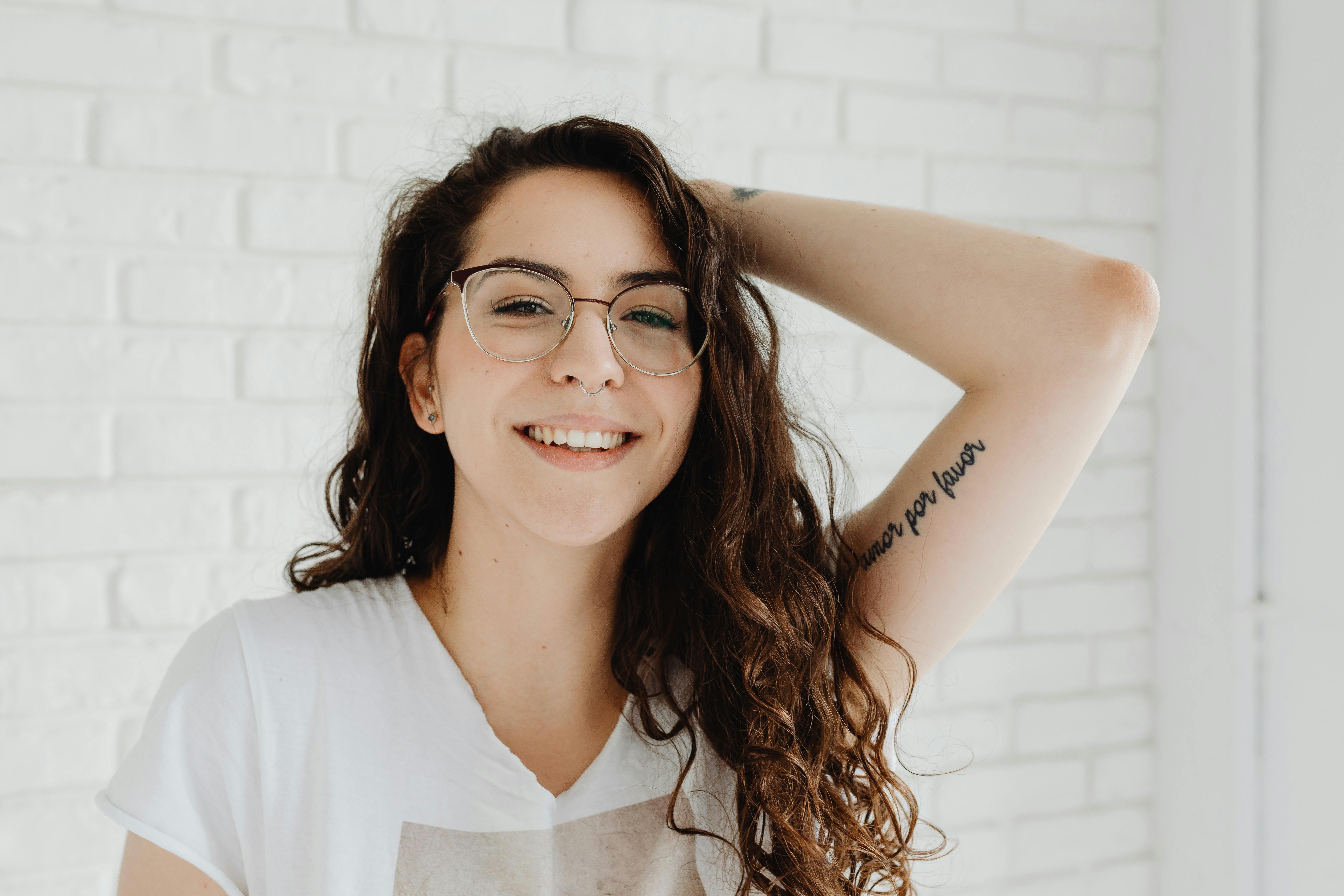 一位戴着眼镜和纹身、穿着白色衬衫的年轻女子的肖像