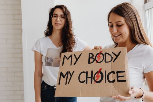 Free Two women advocating for bodily autonomy with a handmade sign indoors. Stock Photo