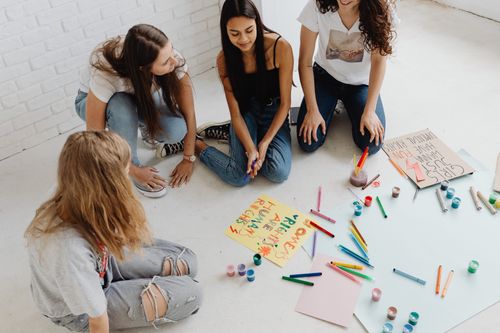 Free Young women engaged in painting protest signs, fostering creativity and empowerment indoors. Stock Photo