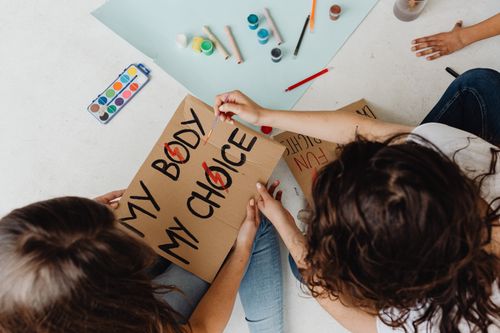 Free Women creating protest signs with creative designs and paints on cardboard. Stock Photo