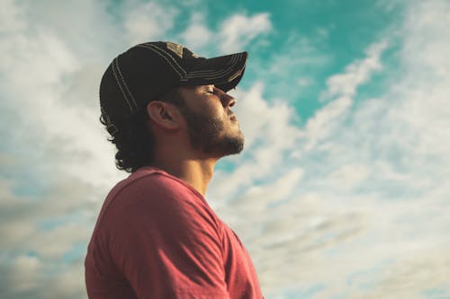 Uomo Che Indossa Cappello Nero Con Gli Occhi Chiusi Sotto Il Cielo Nuvoloso