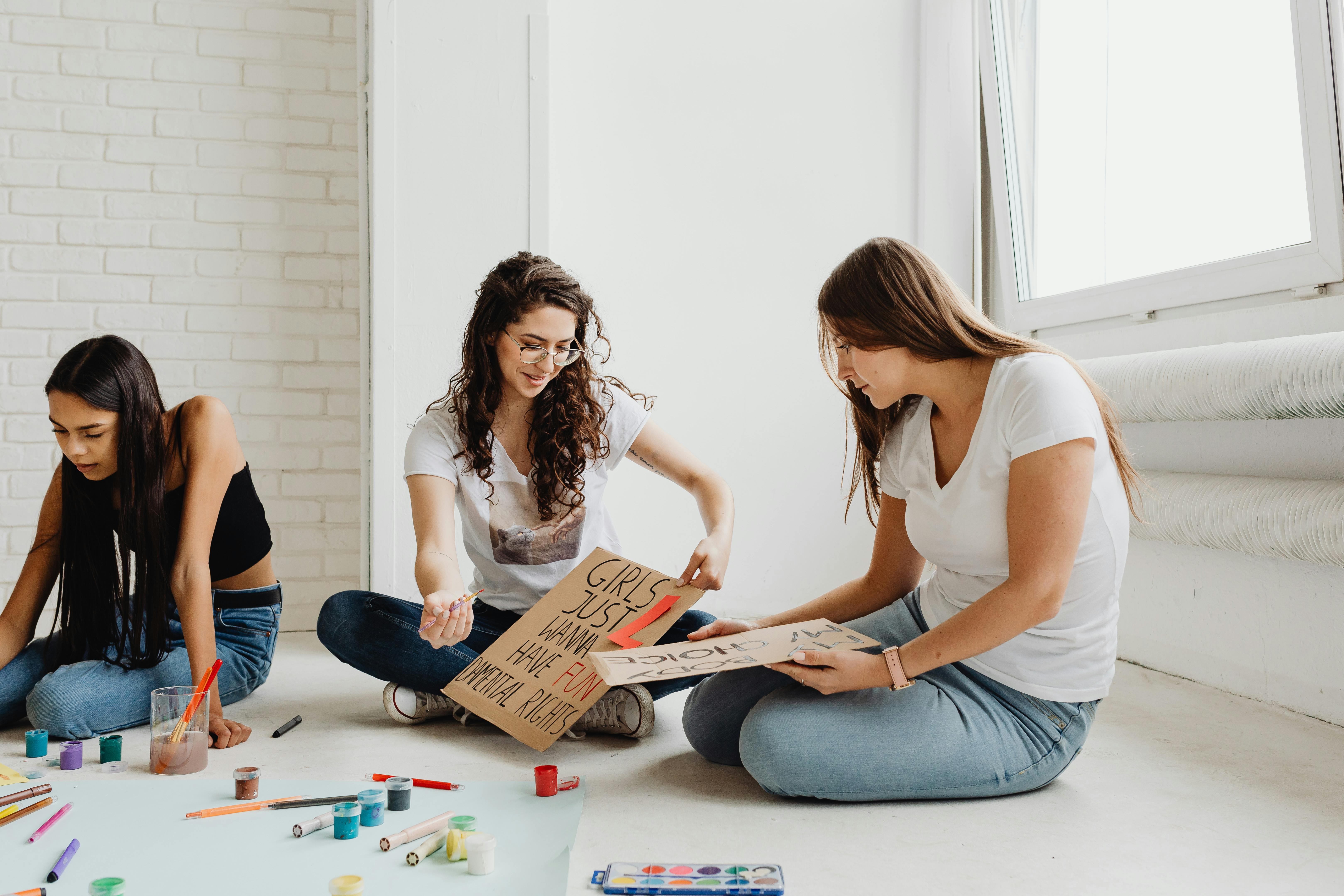 Women Sitting on the Floor Holding a Cardboards