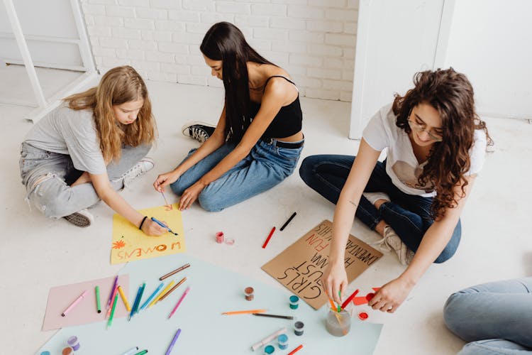 Women Writing On Placards While Sitting On The Floor