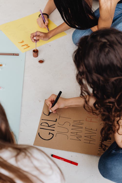 Curly Haired Person Writing on a Cardboard