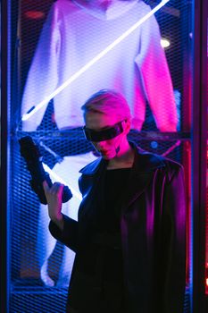 Stylish woman with futuristic eyewear in vibrant cyberpunk setting, holding a gun.