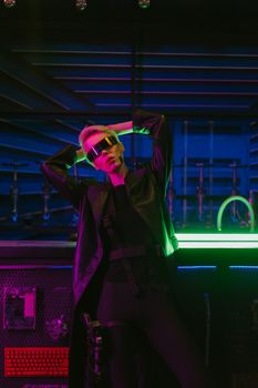Stylish woman in futuristic attire and sunglasses posing in neon-lit cyberpunk setting.. stylish, woman, futuristic