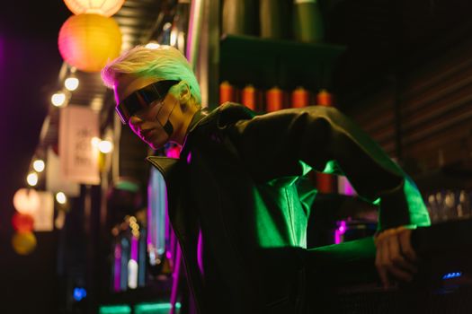 A stylish person with eyewear in a cyberpunk setting lit by vibrant neon lights.