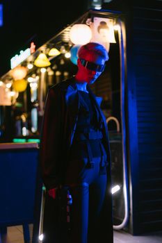 Model in cyberpunk attire with futuristic eyewear in a neon-lit urban setting.. model, cyberpunk, attire