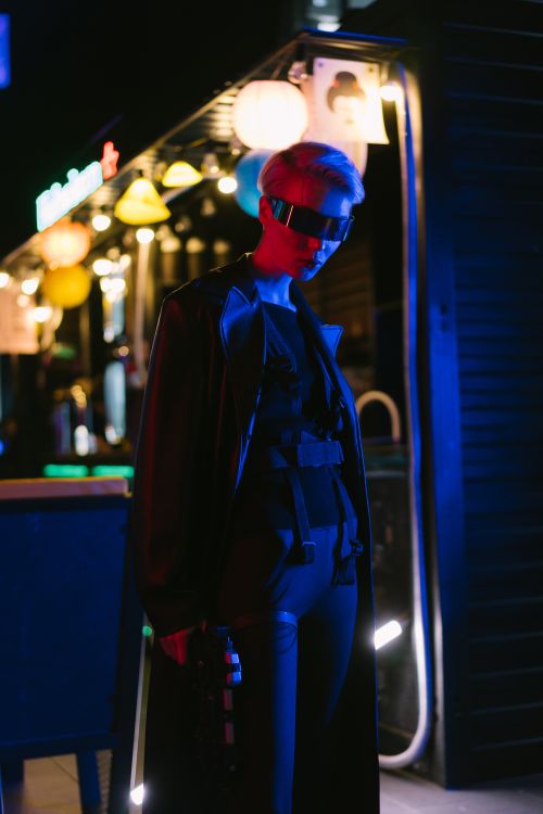 Free Model in cyberpunk attire with futuristic eyewear in a neon-lit urban setting. Stock Photo