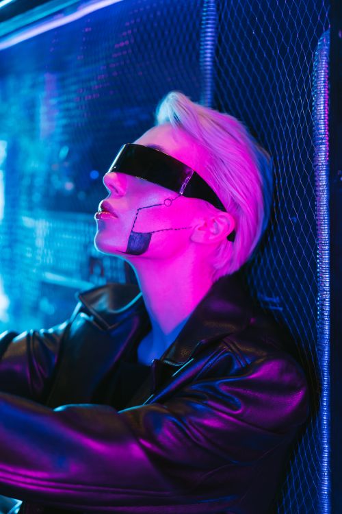 Free Stylish woman in cyberpunk eyewear posing in vibrant neon lighting. Stock Photo