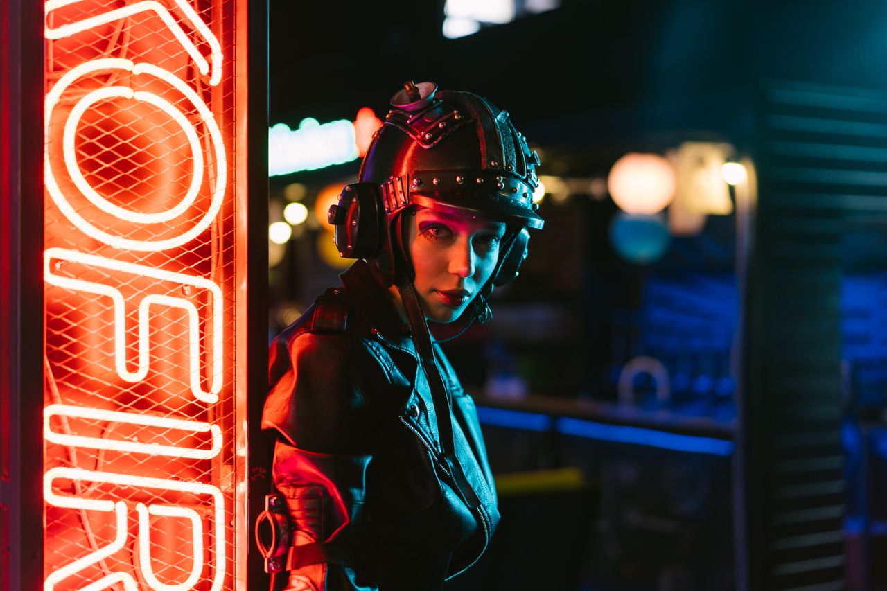woman in cyberpunk attire standing by neon sign in an urban setting